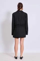 Blazer marrón con solapas de muesca, cierre frontal con lazo y mangas largas. Presenta volados a lo largo de las costuras laterales del pantalón a juego.