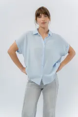Camisa celeste amplia de manga corta, con cuello clásico y botones al frente.