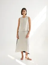 Falda midi de lino color beige, tipo portafolio, con diseño envolvente que cruza al frente y se ajusta con botones en la cintura.