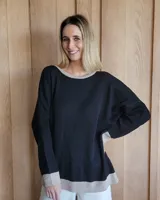 Buzo negro de punto con cuello redondo y manga larga. Tiene una estrella blanca estampada en la espalda y ribetes en color beige en cuello, puños y ruedo.