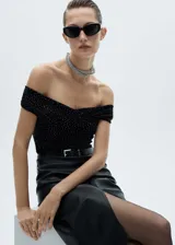 Top negro de tejido de punto con cuello barco, manga corta, diseño entallado y detalle de strass.