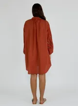 Vestido corto color ocre, con cuello mao, mangas largas abullonadas con detalle de encaje y corte evasé.