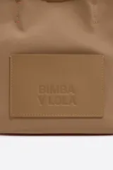 Bolso tote pequeño color marrón claro, de la marca Bimba y Lola, modelo Chihuahua. Tiene doble asa corta y correa larga extraíble. Presenta un bolsillo externo con parche con el logo de la marca.