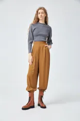Pantalón babucha color marrón de crepe viscosa con cintura alta y elástico en la espalda. Presenta bolsillos laterales y cierre invisible en el lateral. El ruedo tiene elástico interno.