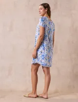 Camisón corto de tejido suave con estampado floral en tonos celeste y azul. Tiene mangas cortas, escote redondo con ribete gris y detalle plisado en el delantero.