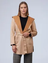 Chaqueta color beige de suede, marca Joan Vass. Cuello solapa, delantera con bolsillos. Cintura con pasadores y lazo de ajuste.