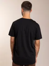 Remera color crema de algodón con cuello redondo y manga corta. Tiene un pequeño bordado de un pájaro rojo en el pecho.