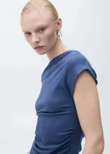 Top azul de tejido de algodón con modal y elastano, de corte entallado, con cuello asimétrico y cintura drapeada.