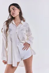 Camisa color crudo con bordados de lentejuelas plateadas en forma de hojas.
