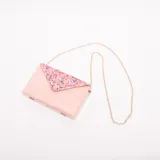 Sobre o clutch rectangular color rosa pálido, con solapa triangular decorada con lentejuelas multicolores. Incluye una cadena fina dorada para usar como bandolera.