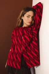 Cárdigan tejido con diseño de rombos rojos y negros, con mangas largas y cierre frontal con botones.