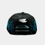 Gorro estilo trucker negro con paneles traseros de malla. Presenta un bordado frontal de una letra 'A' estilizada en blanco y contornos de llamas bordadas en azul brillante alrededor del frente y la visera.