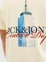 Remera color crema de manga corta con cuello redondo y calce holgado. Estampa en la espalda con el logo de Jack & Jones y un edificio.