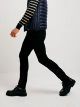 Pantalón de jean negro, corte ajustado (skinny), con tiro medio y cierre de botón y cremallera.