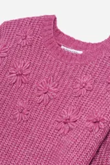 Sweater tejido de punto color fucsia con cuello redondo y mangas largas abullonadas. Presenta apliques de flores en relieve en el frente y en las mangas.