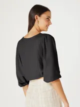 Blusa beige con escote en V, mangas 3/4 abullonadas y cierre frontal con botones.