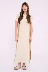 Vestido largo de tejido de punto acanalado color beige claro, con paneles laterales lisos en color marrón. Tiene mangas cortas y cuello redondo.