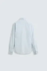 Camisa celeste a rayas verticales, de corte regular fit, con cuello italiano abierto, mangas largas con puños abotonados y cierre frontal con botones.