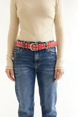 Cinturón rojo de cuero con tachas plateadas y hebilla metálica plateada.