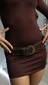 Cinturón marrón de cuero sintético con tachas metálicas y hebilla ovalada de metal color bronce.