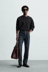 Jersey negro de corte boxy fit, tejido en hilatura con mezcla de algodón y 13% de cashmere. Tiene cuello redondo, manga larga y acabados en rib.