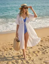 Kaftan blanco largo con mangas cortas y abertura central. Presenta apliques de puntilla en el escote, cintura y ruedo. Se ata en la cintura con un lazo.