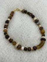 Collar corto de cuentas de piedra natural en tonos marrón, beige y blanco, con detalles dorados.