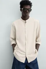 Camisa color beige claro de lino y algodón, corte relaxed fit, cuello mao, manga larga con puños abotonados y cierre frontal con botones. Marca Zara.