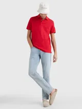 Chomba roja Tommy Hilfiger 1985 de corte regular, con cuello tipo chomba, cartera de dos botones, logo de Tommy Hilfiger bordado en el pecho y detalles distintivos de la marca.