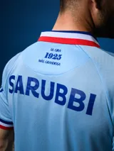 Camiseta de fútbol celeste con cuello y mangas con detalles en azul y rojo. Incluye logo de Umbro, escudo del Club Nacional de Football y sponsor Antel.