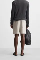 Bermuda regular fit negra confeccionada en tejido de lino. Cintura elástica ajustable con cordón y pliegues frontales. Bolsillos frontales y detalle de bolsillos traseros de plastrón.
