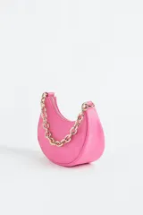 Cartera de hombro chica color rosa con correa de cadena gruesa de metal dorada y cierre.
