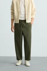 Pantalón verde militar de corte carrot fit, confeccionado en tejido de algodón. Cuenta con cintura elástica ajustable con cordón, bolsillos frontales y un bolsillo trasero de plastrón.