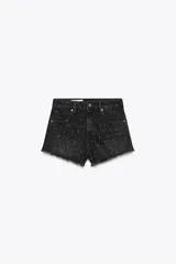 Short de jean negro con lavado gastado y pequeñas estrellas blancas estampadas. Tiene tiro alto, corte recto y terminación desflecada.
