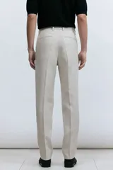 Pantalón de traje de lino color beige, corte slim fit, con cierre y corchete oculto, bolsillos laterales y traseros ribeteados.