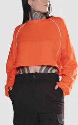 Remera corta naranja con mangas cortas abullonadas y ribete blanco en cuello, mangas y laterales.
