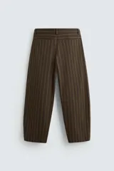 Pantalón marrón con finas rayas verticales negras, de corte amplio tipo balloon fit, con bolsillos laterales y traseros ocultos. Cierre frontal con cremallera y botonadura cruzada.