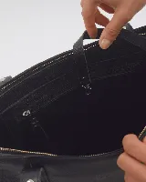 Bolso tote negro de cuero con tachas plateadas en las tiras. Tiene cierre superior, bolsillo interior y llavero.