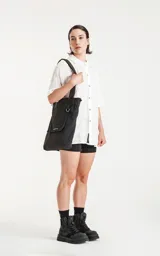 Bolso tote negro de tela técnica de microfibra de secado rápido, con espacio principal para llevar pertenencias. Cuenta con un elástico ajustable con tanca y contiene dos bolsillos, uno interno con cierre y otro externo con velcro.