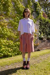 Bermuda a la rodilla con rayas verticales color salmón y gris. Tiene tiro medio, calce relajado, cierre con botones y ganchito oculto en la cintura, y bolsillos laterales.