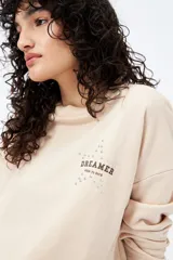 Buzo color marrón de corte relajado confeccionado en tejido de algodón con interior suave al tacto. Presenta detalle de estrella con tachas en la espalda y bordado delantero con la frase Dreamer – Born to rock.