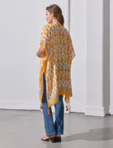 Kimono tejido color naranja con estampado geométrico en blanco y celeste, y terminación con borlas.