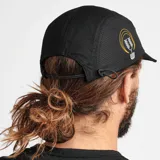 Gorro tipo camper negro con textura microperforada, visera corta y construcción plegable. Presenta un bordado frontal de un sol estilizado en tonos naranjas y un bordado lateral de una serpiente con una hoja en tonos amarillos y blancos.