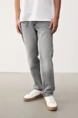 Jean gris de cinco bolsillos en denim de algodón elástico con cintura estándar y cierre con botón. Piernas rectas con buena libertad de movimiento en muslo y rodilla.