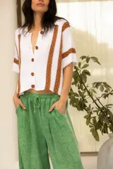 Camisa tejida de algodón color blanco con rayas verticales color tostado, cuello camisero, manga corta y bolsillos al frente.