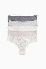 Pack de cinco bombachas tipo brazilian de tiro bajo con refuerzo interior y corte alto atrás. Incluye bombachas lisas en gris oscuro, gris claro, blanco y rosa pálido, y una bombacha estampada con flores pequeñas y ribete de encaje. Todas tienen un pequeño moño decorativo en el centro.