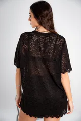 Remerón o vestido corto de encaje negro, con mangas cortas y terminaciones festoneadas. El tejido es transparente.