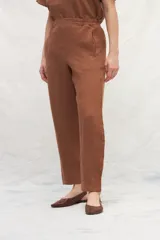 Pantalón de lino color marrón, de corte recto y tiro alto, con cintura elástica y bolsillos laterales.