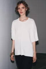 Remera blanca de punto liso, corte amplio, cuello redondo y manga corta.