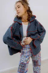 Chaqueta corta de paño de lana azul con detalles de crochet en rojo y verde.